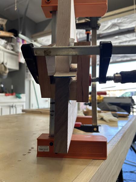 Clamped for glue-up. I use home made cauls designed to keep the board halves aligned correctly. The glue joint is slippery because there is glue on both sides of the inserted maple strip.